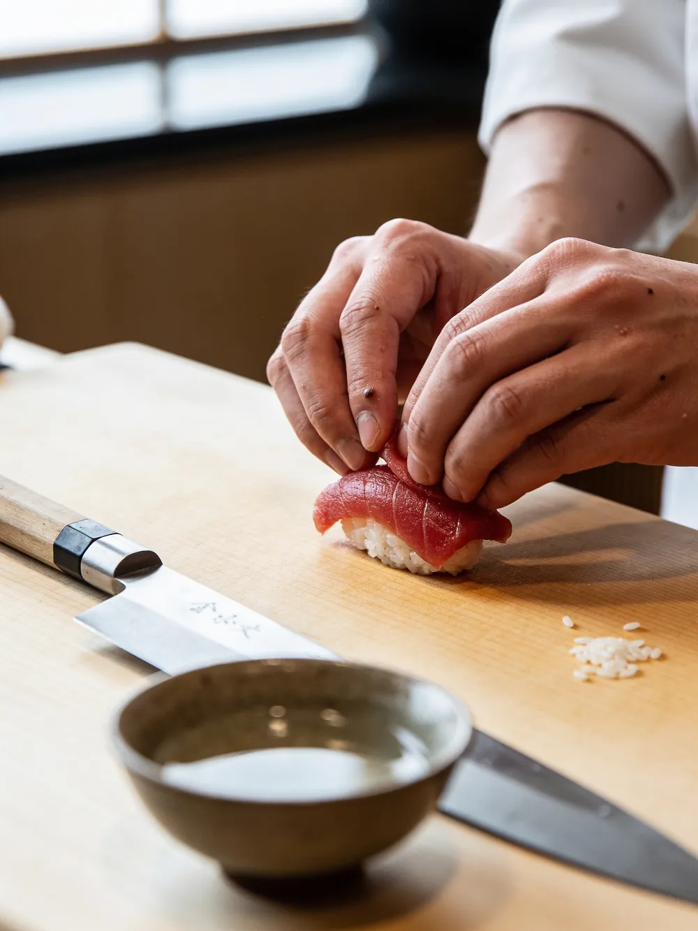 Le mani dello chef che formano un nigiri di tonno